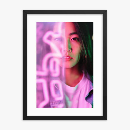 Portrait of young woman lit by pink neon light 18x24 in Poster With Black Frame